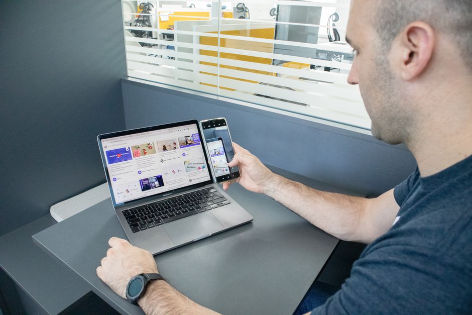 Zaposlenik multitaska s laptopom i pametnim telefonom u modernom uredu